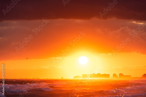 Dramatic orange red sunset in Santa Rosa Beach, Florida with Pensacola coastline coast cityscape skyline in panhandle with ocean gulf mexico