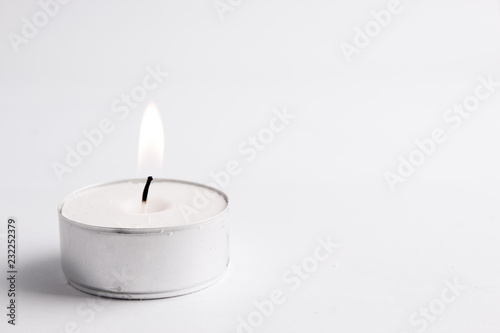 white tealight candle isolated in white, clean backgroung; with flame