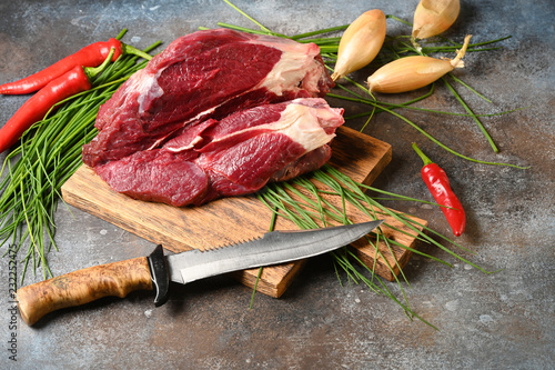 Fresh dark meat with ingredients for cooking on brown wooden cutting board. Hunting composition. Wildanimal hunting.