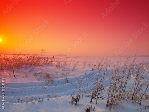 Sunset and snow-covered grass. Winter, Russia, Ural, Perm Region