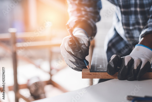 Confident wood worker expert. Young man working at factory. Skilled carpenter cutting a piece of wood in his woodwork workshop.