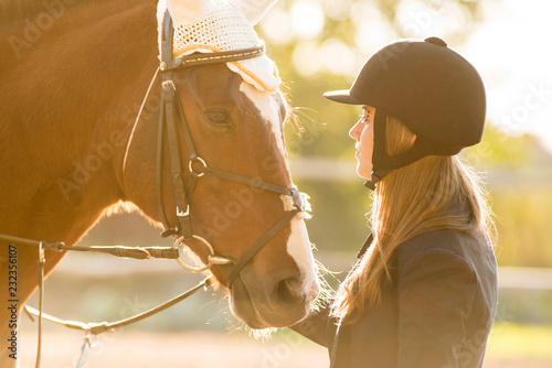 Dziewczyna jeździec stoi w pobliżu konia i przytula konia. Motyw konia