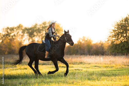 Girl equestrian rider riding a beautiful horse in the rays of the setting sun. Horse theme 