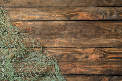 Fishing net on wooden background, top view with space for text