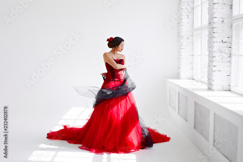 A young woman in a red dress is dancing. Latin style. Isolate on white