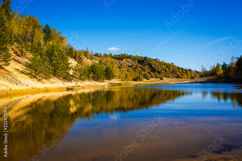 Blue lake on a bright Sunny day, the reflection of sandy shores in the water. Wide river valley in a mountainous area