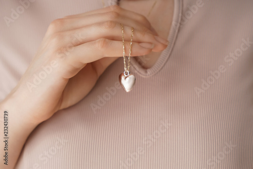 Woman wearing heart-shaped pendant, closeup