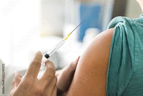 Vaccine or flu shot in injection needle. Doctor working with patient's arm. Physician or nurse giving vaccination and immunity to virus, influenza or HPV with syringe. Appointment with medical expert.