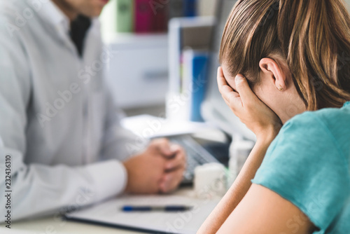 Sad patient visiting doctor. Young woman with stress or burnout getting help from medical professional or therapist. Anxiety, depression or mental health problems concept. Physician telling bad news.