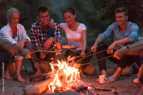 young friends relaxing around campfire