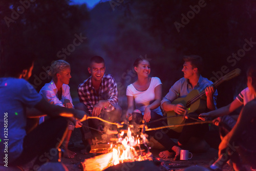 young friends relaxing around campfire