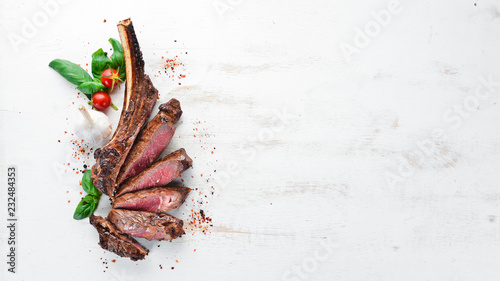 Steak on the bone. tomahawk steak On a white wooden background. Top view. Free copy space.