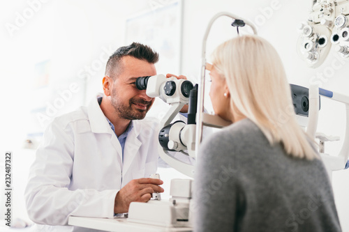 Optician examining woman's eyes with a machine.