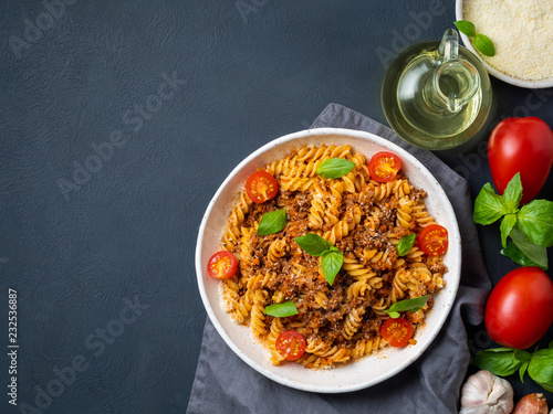 Bolognese pasta. Fusilli with tomato sauce, ground minced beef, basil leaves. Traditional italian cuisine. Top view, copy space.
