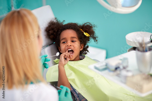 Little child in dental chair show with finger tooth
