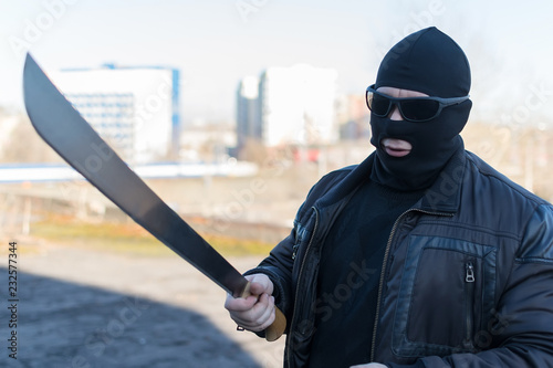 a thug with glasses and a balaclava threatening with a large knife