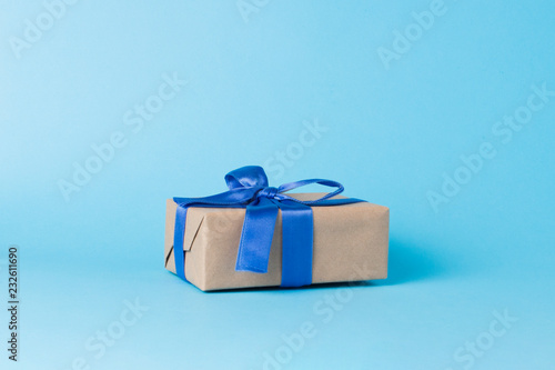 Gift box with blue ribbon on a blue background. Minimalism. Concept of a gift for loved ones