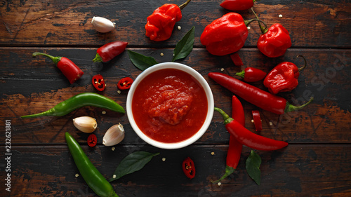 spicy hot sweet chili sauce with mix of chilli pepper, garlic and tomatoes on rustic wooden background