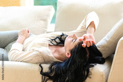 Sick young woman with a fever or illness in a bright interior room