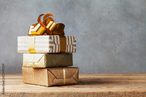 Heap of golden gift or present boxes on wooden table. Composition for birthday or christmas.