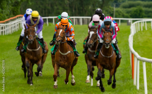 Head on view of galloping race horses and jockeys racing