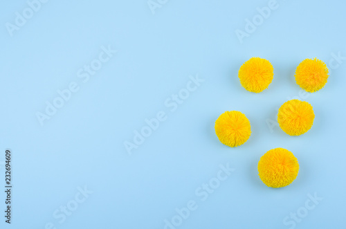 Yellow pom-pom on blue background with copy space 