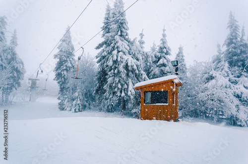 Empty t-bar lift and wooden building at snowfall