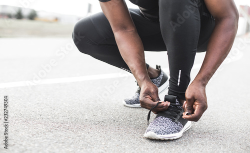 Young sportsman tying shoelaces on sport shoes. Fit, fitness, exercise, workout and healthy lifestyle concept. free space for text