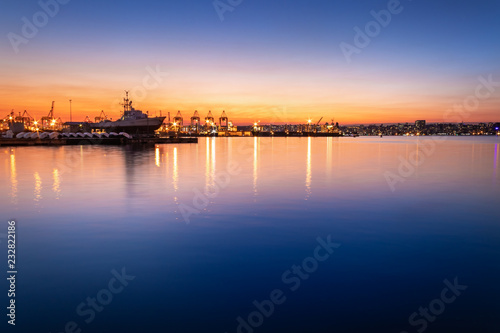 View of the ships in Durban harbor at sunset with colored lights reflecting in the water, Durban, South Africa.