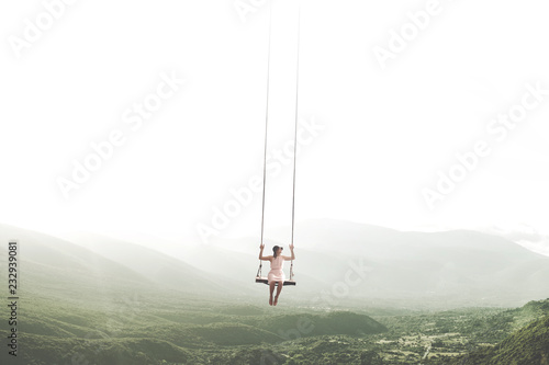 surreal moment of a woman having fun on a swing hanging from the sky