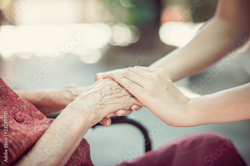 Hand of eldery woman with her caregiver at home. Home care or Elderly care concept.