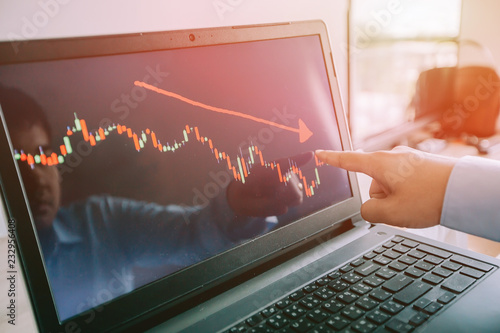 Hand of man point to the laptop show financial market chart graphic going down. Stock market concept.