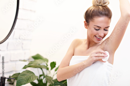 Young woman using deodorant in bathroom