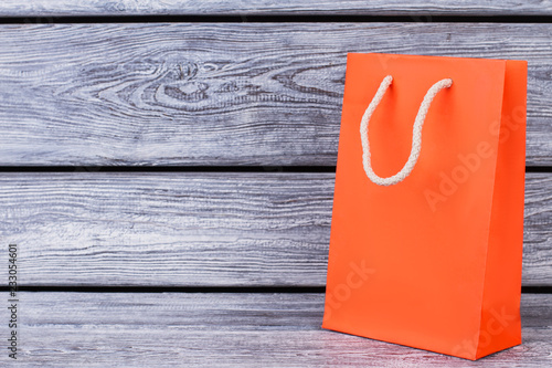 Orange paper bag with copy space. Gift packet of orange color on rustic wooden background with text space.