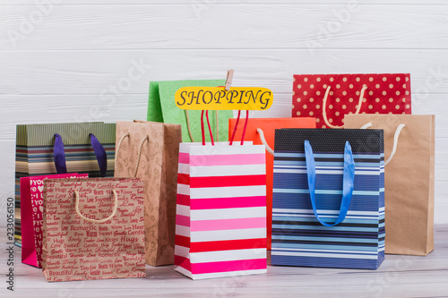 Assorted paper shopping bags background. Variety of paper bags and card with inscription shopping.