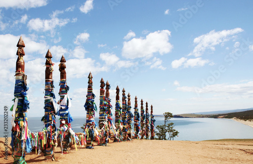Vivid colored ribbons Hadak tied on posts of wish. Wooden ritual pillars. Sacred place of Buddhist shamans, Baikal, Russia. Mystical traditions of Asia.