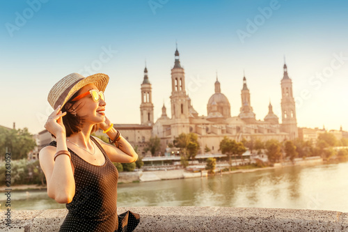 Happy traveler in hat on the main Piedra bridge over Ebro river in Zaragoza against the background of the Basilica Del Pilar