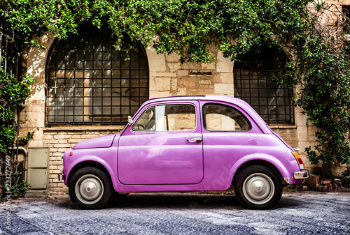 Pink Fiat 500 Oldtimer typical italian parking in front of a wall