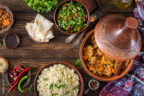 Traditional tajine dishes, couscous and fresh salad on rustic wooden table. Tagine lamb meat and pumpkin. Top view. Flat lay