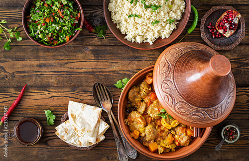 Traditional tajine dishes, couscous and fresh salad on rustic wooden table. Tagine lamb meat and pumpkin. Top view. Flat lay