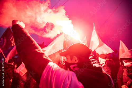 People carry Polish flags and burn flares as they walk across the Poniatowski Bridge during a march marking the 100th anniversary of Polish independence in Warsaw, Poland November 11, 2018. 