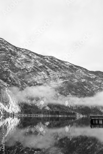 Greyscale image of old wooden pier on calm winter lake