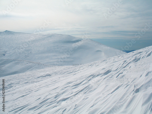 White snow covered mountain peaks on high. Cold winter background. In the Carpathians in Ukraine.