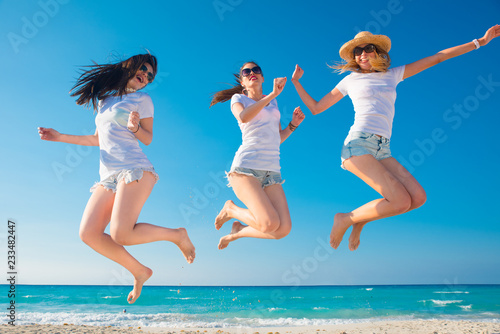 Tres mujeres muy sexys con camiseta blanca saltando y disfrutando un día de verano.