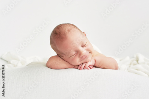 Cute newborn baby lies swaddled in a white blanket. Baby goods packaging template. Closeup portrait of newborn baby with smile on face. Healthy and medical concept. 