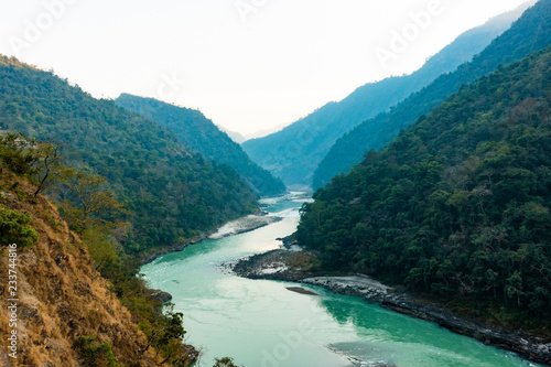 Spectacular view of the sacred Ganges river flowing through the green mountains of Rishikesh, Uttarakhand, India.