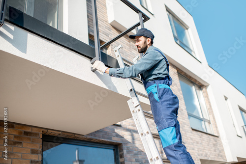 Builder in blue uniform mounting aluminium fence on the balcony of the new building