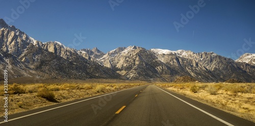 Driving Iconic California State Highway 395 in Owens Valley on Eastern Flanks of Sierra Nevada Mountains with Distant Mount Whitney on Horizon