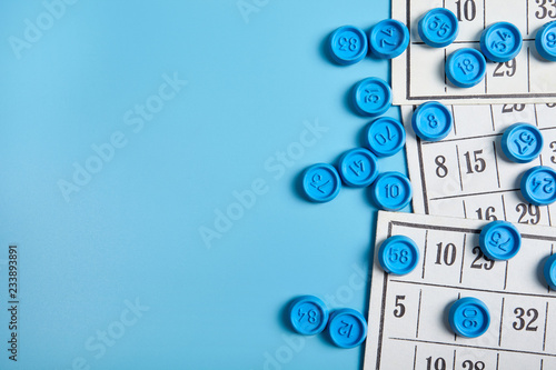 Bingo balls and cards on blue background with copy space.