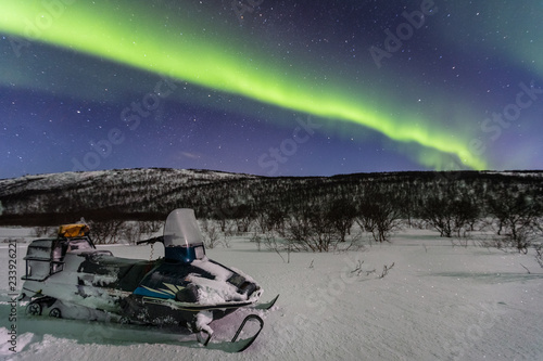 Beautiful green northern lights and snowmobile on foreground